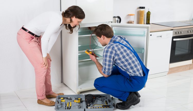 Beautiful,Housewife,Looking,At,Male,Worker,Repairing,Refrigerator,In,Kitchen